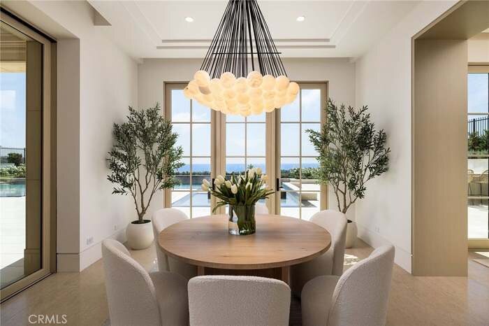 Dining room with round table, statement chandelier, and garden views