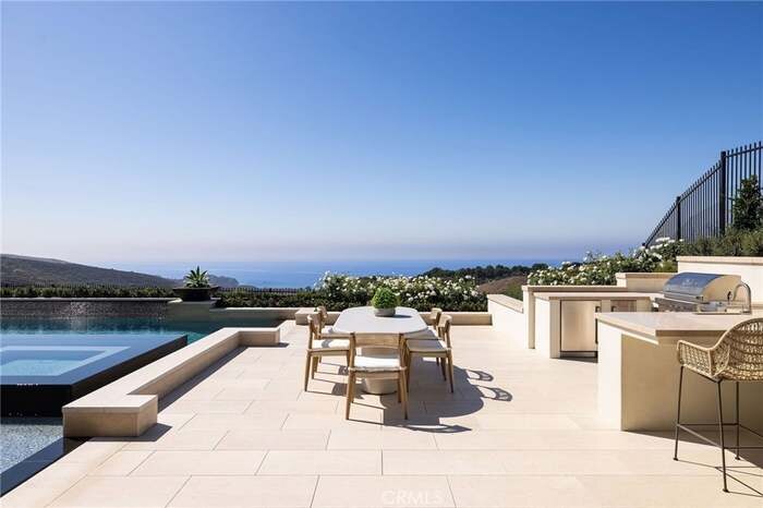 Outdoor dining terrace beside a pool with distant water views